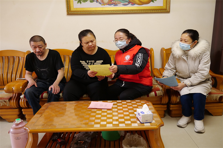 宋海贤（右一）和志愿者入户发放暖心服务宣传单和明白卡。（摄影：胡建华）
