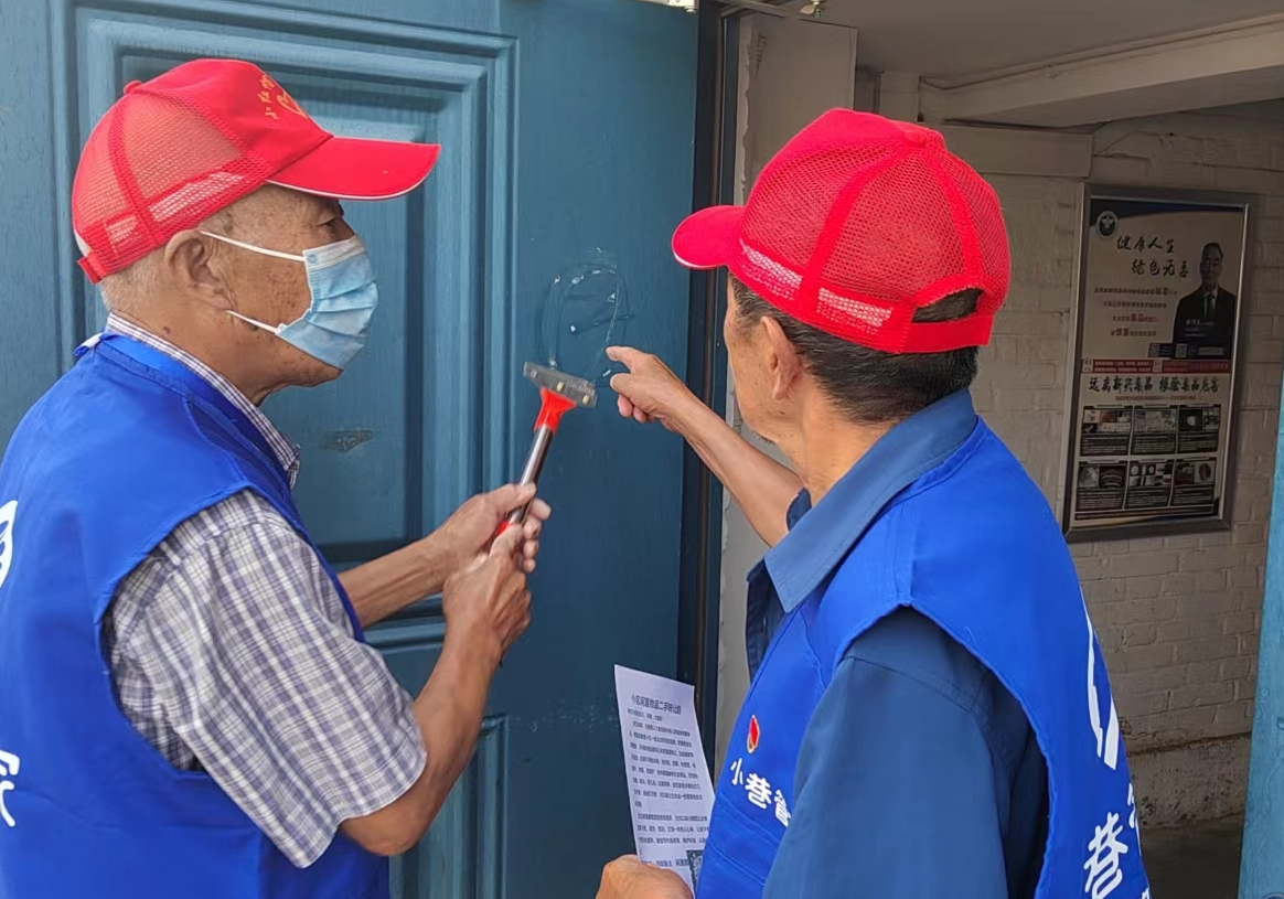离退休党员干部协助社区铲除小广告。（来源：包头市青山区委组织部）